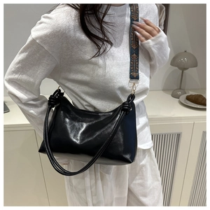 Detail of black faux leather crescent tote bag with wide bohemian embroidered strap