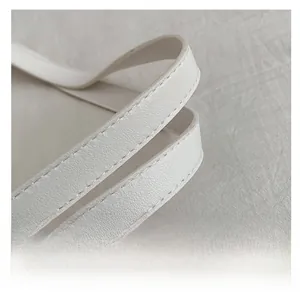 Détails macro de la double couture renforcée et du cuir grainé blanc sur la poignée du cabas