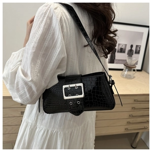 Close-up of black crocodile pattern crossbody bag with a large silver knit buckle detail