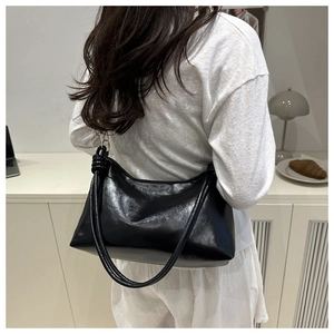 Détail d'un sac à bandoulière hobo noir avec nœud décoratif porté par un mannequin