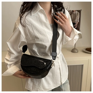 Detail of black crocodile texture saddle bag with wide adjustable nylon shoulder strap