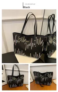 Détail d'un grand cabas noir avec broderies ondulées colorées et logo métallique