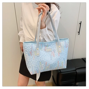 Detail of light blue tote bag featuring wavy rainbow embroidery and letter embossing
