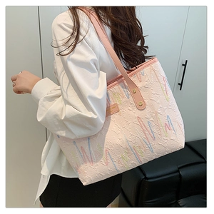 Detailed side view of light pink jacquard tote bag with colorful wave embroidery and studs
