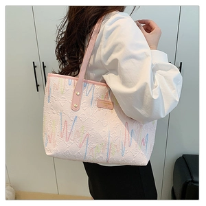 Détail du cabas rose à rayures avec broderies colorées et plaque de marque dorée