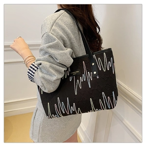 Détail du sac cabas noir montrant des broderies colorées et une bandoulière en cuir