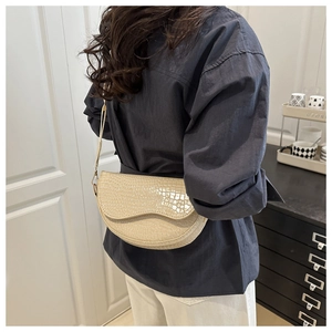 Detail shot of cream white saddle bag with crocodile embossed texture and long shoulder strap