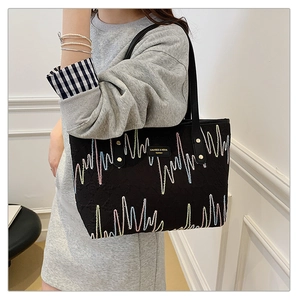 Détail du sac cabas noir avec broderies ondulées colorées et étiquette de marque chic