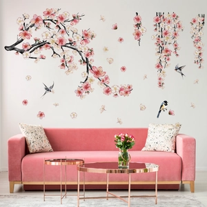 Detail of pink floral wall stickers with birds and cherry blossoms above a velvet sofa