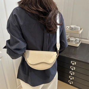 Chic beige crocodile embossed saddle bag with wide shoulder strap on model back