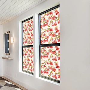 Detail of floral window film with pink watercolor flowers and green leaves on glass