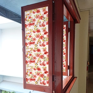 Close-up of translucent window film with red floral and gold leaf patterns on wood frame