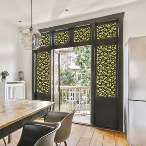 Close-up of decorative static window film with elegant white floral and leaf patterns