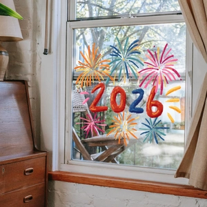 Detail of 2026 firework static window clings on glass with festive home interior background