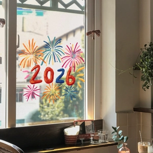 Detail of 2026 New Year firework window static stickers on glass with a cozy indoor view