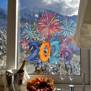 Close-up of 2026 New Year fireworks window decals on glass with snowy mountain view