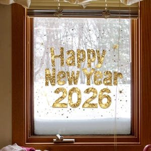 Close-up of golden glitter Happy New Year 2026 window stickers with star ornaments