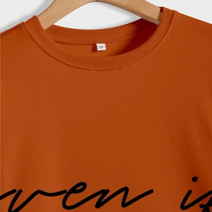 Detail of orange-brown sweatshirt neckline with ribbed collar and script print on cotton fabric