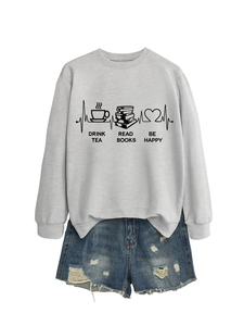 Flat lay of grey sweatshirt with 'DRINK TEA READ BOOKS' print and ripped denim shorts