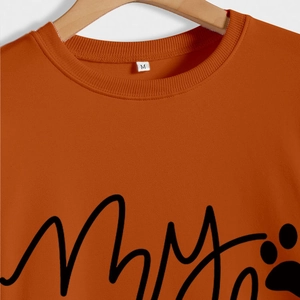 Close-up of orange sweatshirt crewneck with My lettering and paw print detail