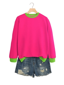 Detail view of pink sweatshirt with green ribbed cuffs and distressed denim shorts set