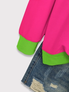 Detail of rose pink sweatshirt with vibrant green ribbed cuffs and denim shorts