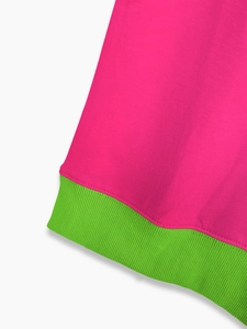 Detailed close-up of pink knit fabric seam and green ribbed cuff stitching on a sweatshirt