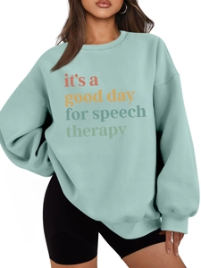 Detalle de sudadera verde menta con estampado colorido 'it's a good day for speech therapy'