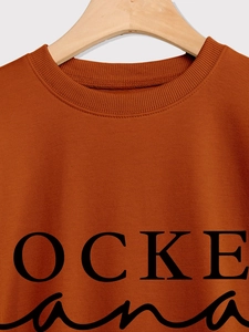 Detail von Rippbündchen und schwarzem Aufdruck auf dem karamell-orangenen Sweatshirt für Damen
