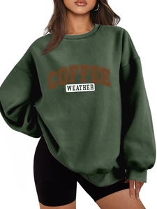 Close-up of the Coffee Weather graphic print on a dark green oversized cotton sweatshirt