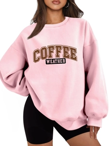 Detail of light pink oversized sweatshirt featuring brown Coffee Weather graphic print