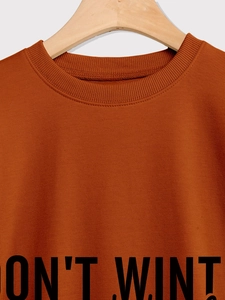 Close-up of the caramel-colored ribbed neckline and printed lettering on a comfy sweatshirt