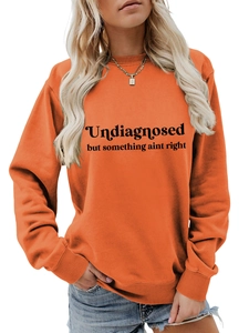 Detail eines orangen Sweatshirts mit schwarzem Textaufdruck und Rippbündchen