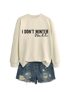 Flat lay of beige sweatshirt with 'I DON'T WINTER Well' text and denim shorts
