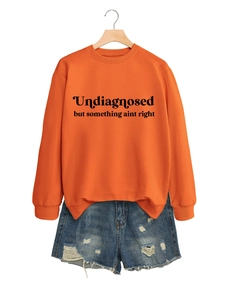 Nahaufnahme von hellem orangefarbenem Sweatshirt und Distressed-Denim-Shorts am Bügel