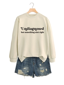 Detail eines beigen Crewneck-Sweatshirts mit schwarzem Textdruck und Distressed-Denim-Shorts