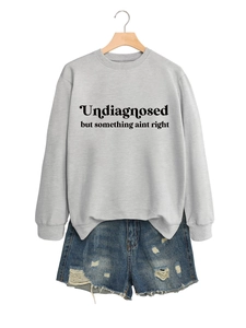 Detail eines grauen Sweatshirts mit schwarzem Spruch und zerrissenen Denim-Shorts vor weißem Grund