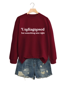 Nahaufnahme von burgunderfarbenem Sweatshirt und blauen Jeans-Shorts an einem Holzkleiderbügel