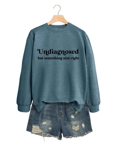 Detail eines dunkelblauen Sweatshirts mit Aufdruck und Distressed-Denim-Shorts am Holzbügel