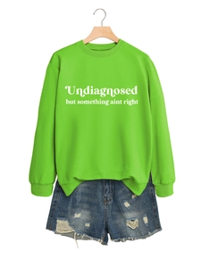 Detailansicht von neongrünem Sweatshirt mit Text und Used-Look Jeans-Shorts am Kleiderbügel