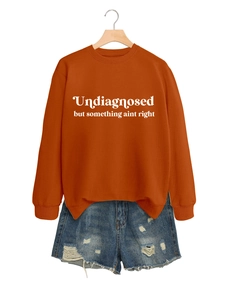 Detail eines brennorangefarbenen Sweatshirts mit weißem Text und blauen Denim-Shorts