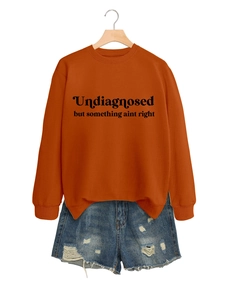 Detail von gebranntem orangefarbenem Sweatshirt mit Text und Denim-Shorts am Bügel