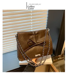 Close-up of coffee brown leather crossbody bag with bow detail and silver chain strap