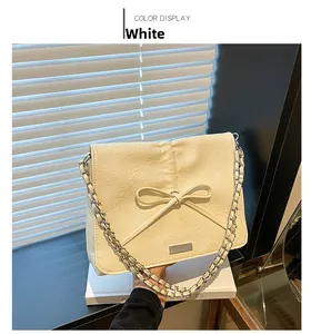Detail of white bow shoulder bag with pleated leather texture and silver chain strap