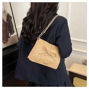 Detail view of stylish tote bag with bow accent and chain leather shoulder strap