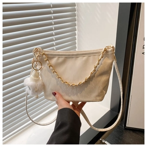 Detail of white nylon tote bag with golden chain strap and soft plush pendant