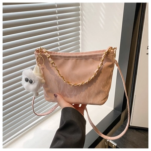 Detailed shot of pink pleated bucket bag featuring golden chain and plush doll pendant