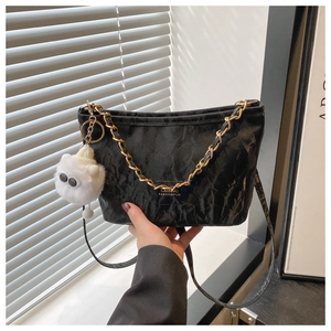 Detail of black wrinkled tote bag featuring golden chain and plush keychain accessory