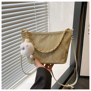 Detail of sage green bucket bag with golden chain and plush sheep charm on shoulder strap