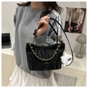 Detail of black pleated tote bag with gold chain and white plush charm on side